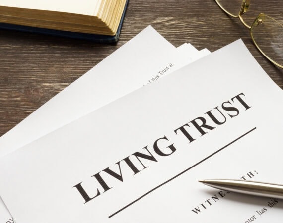 A living trust document on a wooden desk with a pen, eyeglasses, and an open book nearby—an essential part of estate planning under Elder Law in Smithtown, NY.