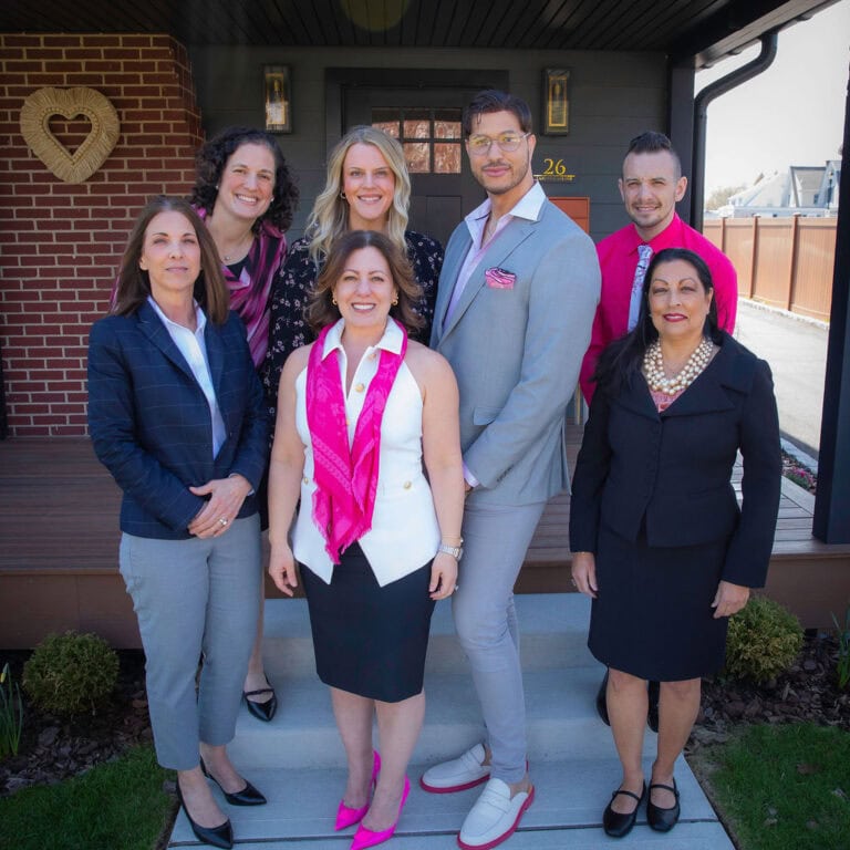 Fratello Law team posing together in professional attire, smiling confidently in the office, representing the legal staff of Fratello Law in New York.