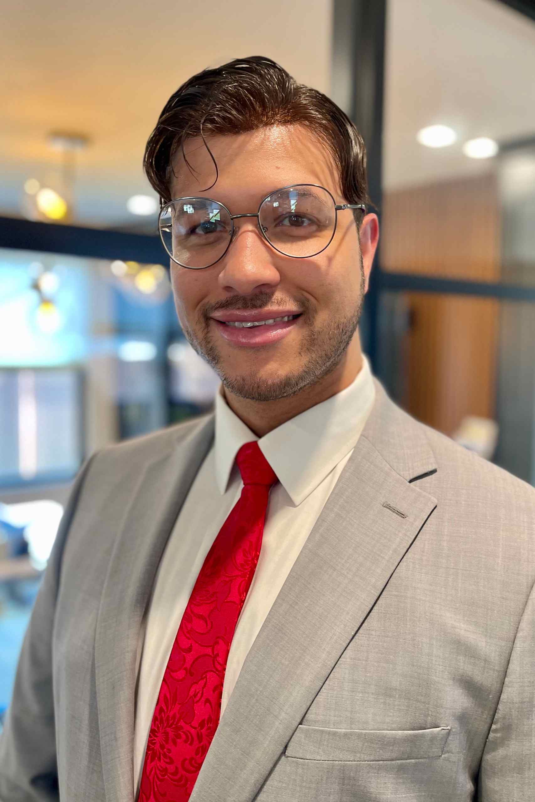 Peyton Gambino, attorney at Fratello Law, smiling confidently in professional attire against a neutral office background, conveying approachability and expertise in legal services.